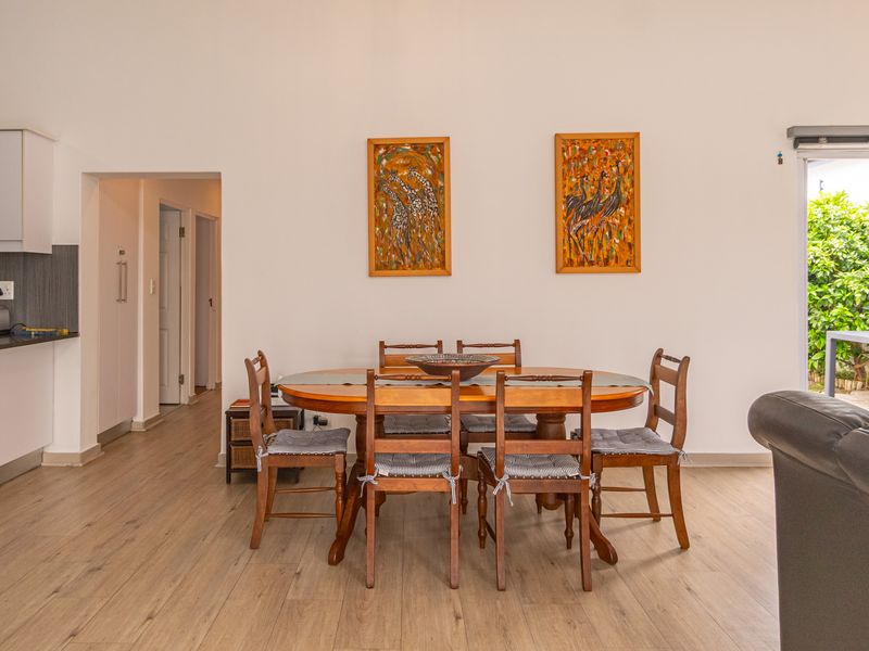 Open-plan living and dining area featuring laminate flooring, a modern kitchen with granite countertops, and direct access to the outdoor patio through sliding doors.