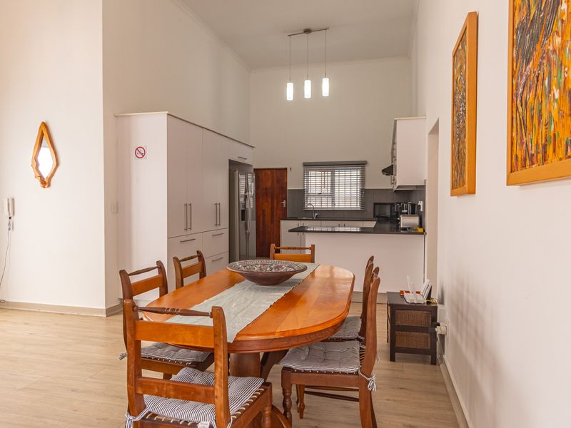 Open-plan dining and kitchen area featuring modern cabinetry, laminate flooring, and a functional kitchen island with ample storage space.