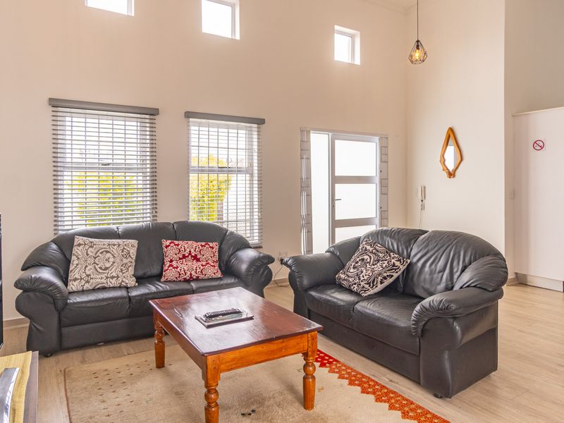 Spacious open-plan living area featuring high ceilings, clerestory windows, laminate flooring, and an integrated kitchen space with modern cabinetry.