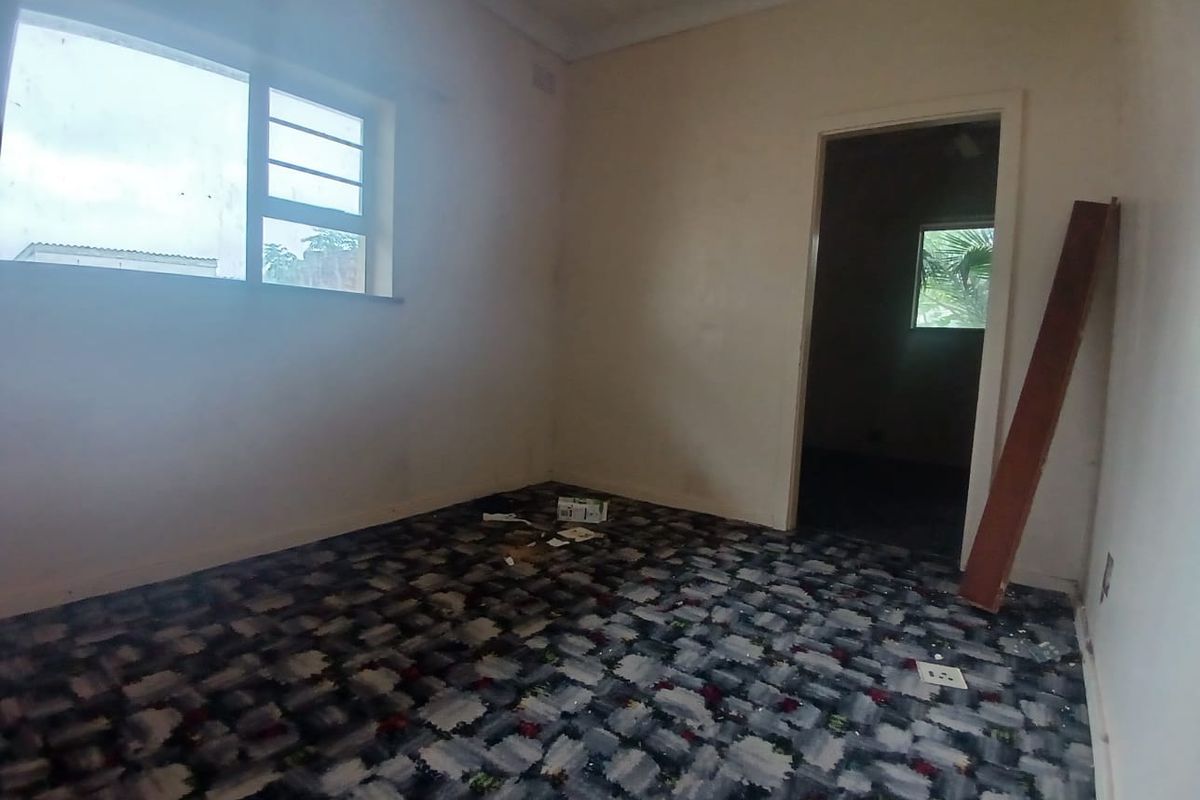 An empty bedroom featuring worn patterned carpeting and plain walls, offering a blank canvas for renovation and modernization.
