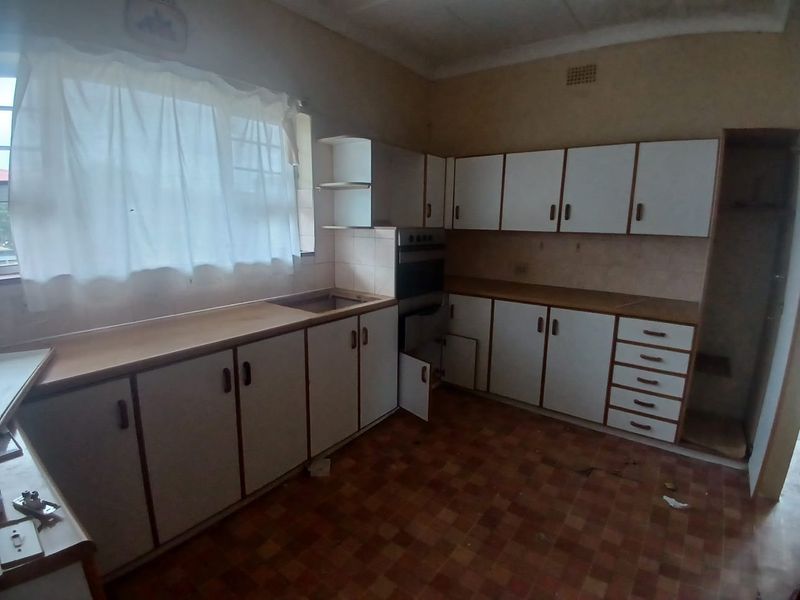 A dated kitchen featuring built-in cabinetry, laminate countertops, and a built-in oven, offering a blank canvas for renovation and modernization.