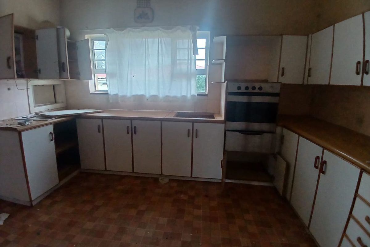 A dated kitchen featuring original built-in cabinetry, laminate countertops, and a built-in oven, offering significant potential for a modern renovation.