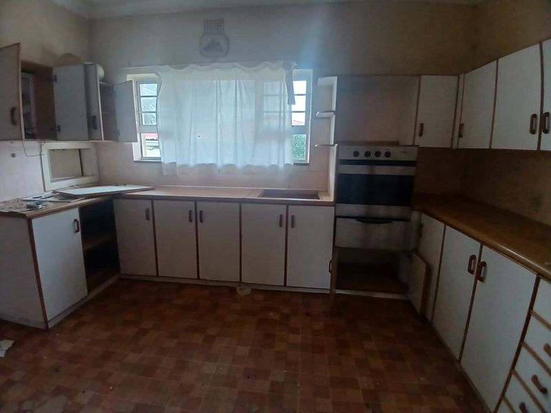A dated kitchen featuring original built-in cabinetry, laminate countertops, and a built-in oven, offering significant potential for a modern renovation.