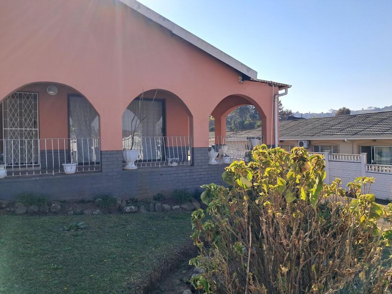 A covered patio area featuring arched masonry columns, metal balustrades, and sliding glass door access to the home interior.