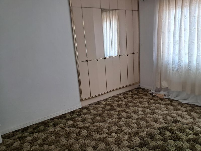A bedroom featuring built-in cupboards and wall-to-wall carpeting, offering a blank canvas for potential modernization and interior updates.