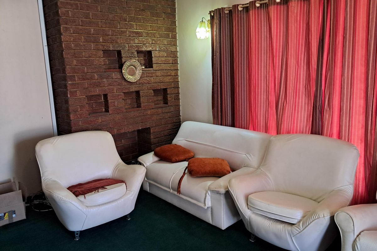 A living room featuring a prominent exposed brick fireplace and wall-mounted lighting fixtures.