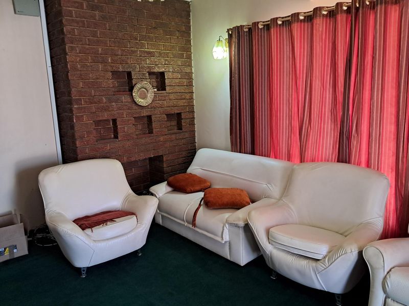 A living room featuring a prominent exposed brick fireplace and wall-mounted lighting fixtures.