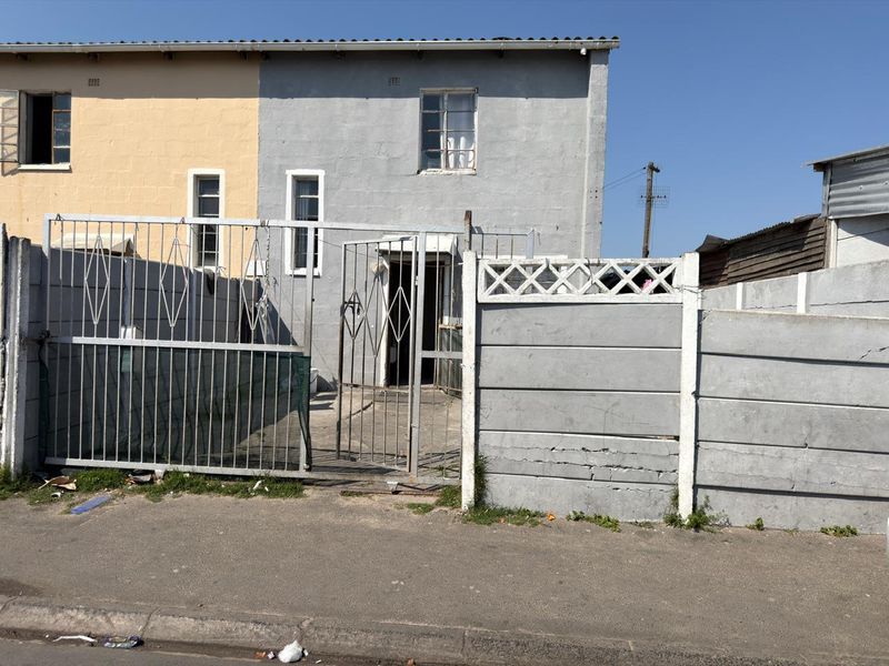 Front elevation of a semi-detached house featuring a metal security gate, precast concrete boundary wall, and steel window frames.