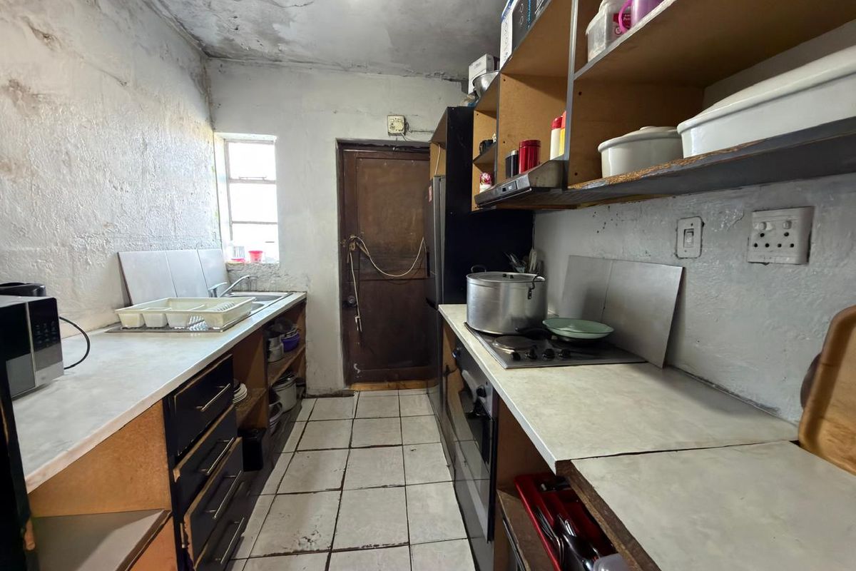 A compact kitchen featuring built-in cabinetry, an electric hob, and an oven, requiring significant cosmetic updates and repairs to the ceiling and wall finishes.
