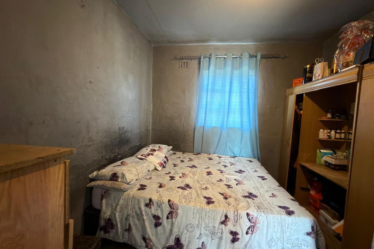 A bedroom featuring a built-in wardrobe and unfinished, stained plaster walls, requiring cosmetic renovation to improve the overall finish and appeal.