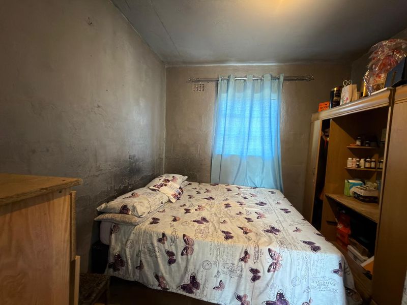 A bedroom featuring a built-in wardrobe and unfinished, stained plaster walls, requiring cosmetic renovation to improve the overall finish and appeal.