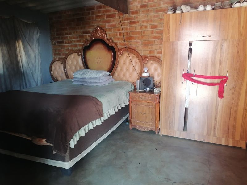 A bedroom featuring exposed brick walls and concrete flooring, requiring cosmetic updates and finishing to improve the overall aesthetic and condition.