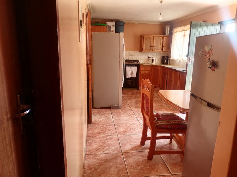 A functional kitchen featuring wooden cabinetry, tiled flooring, and a built-in stove, offering a dated aesthetic with potential for modernization.