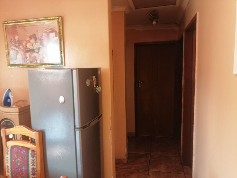 A narrow interior hallway featuring tiled flooring and access to adjacent rooms, showing signs of wear and dated wall finishes.