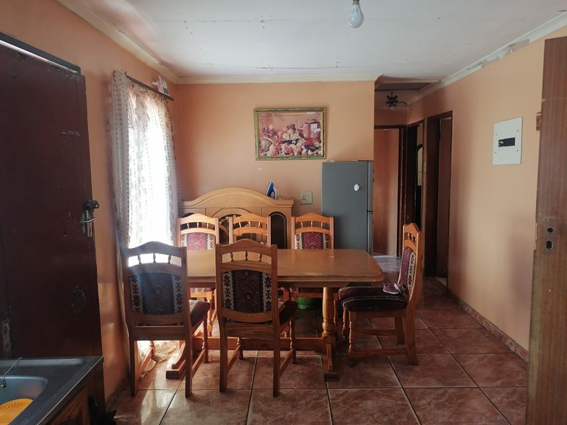 Dining area featuring ceramic floor tiles and access to adjacent rooms, requiring cosmetic updates to the ceiling and wall finishes.