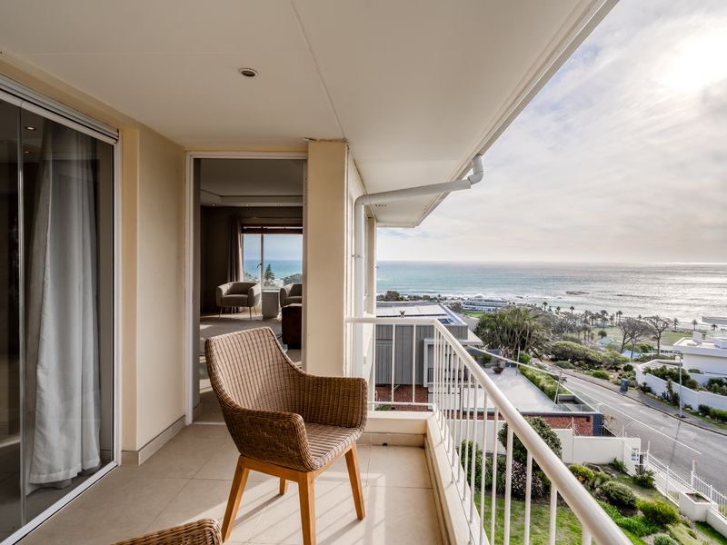 A covered balcony featuring tiled flooring and a metal balustrade, offering expansive coastal and ocean views.