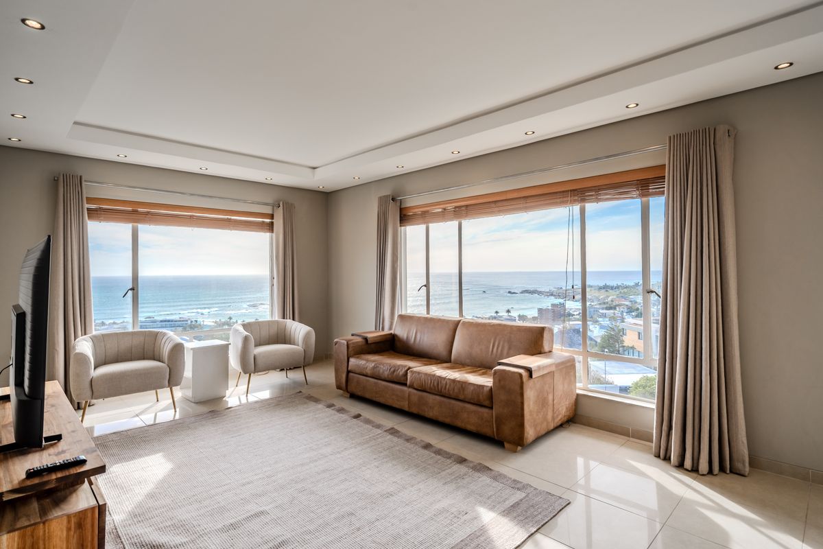 Spacious living room featuring large windows with expansive ocean views, recessed ceiling lighting, and neutral tiled flooring.