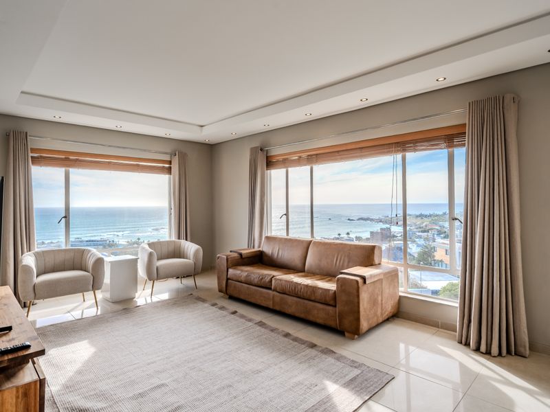Spacious living room featuring large windows with expansive ocean views, recessed ceiling lighting, and neutral tiled flooring.