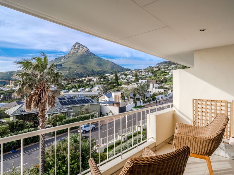 A spacious balcony featuring a metal balustrade and recessed lighting, offering stunning elevated views of the surrounding neighborhood and mountain landscape.