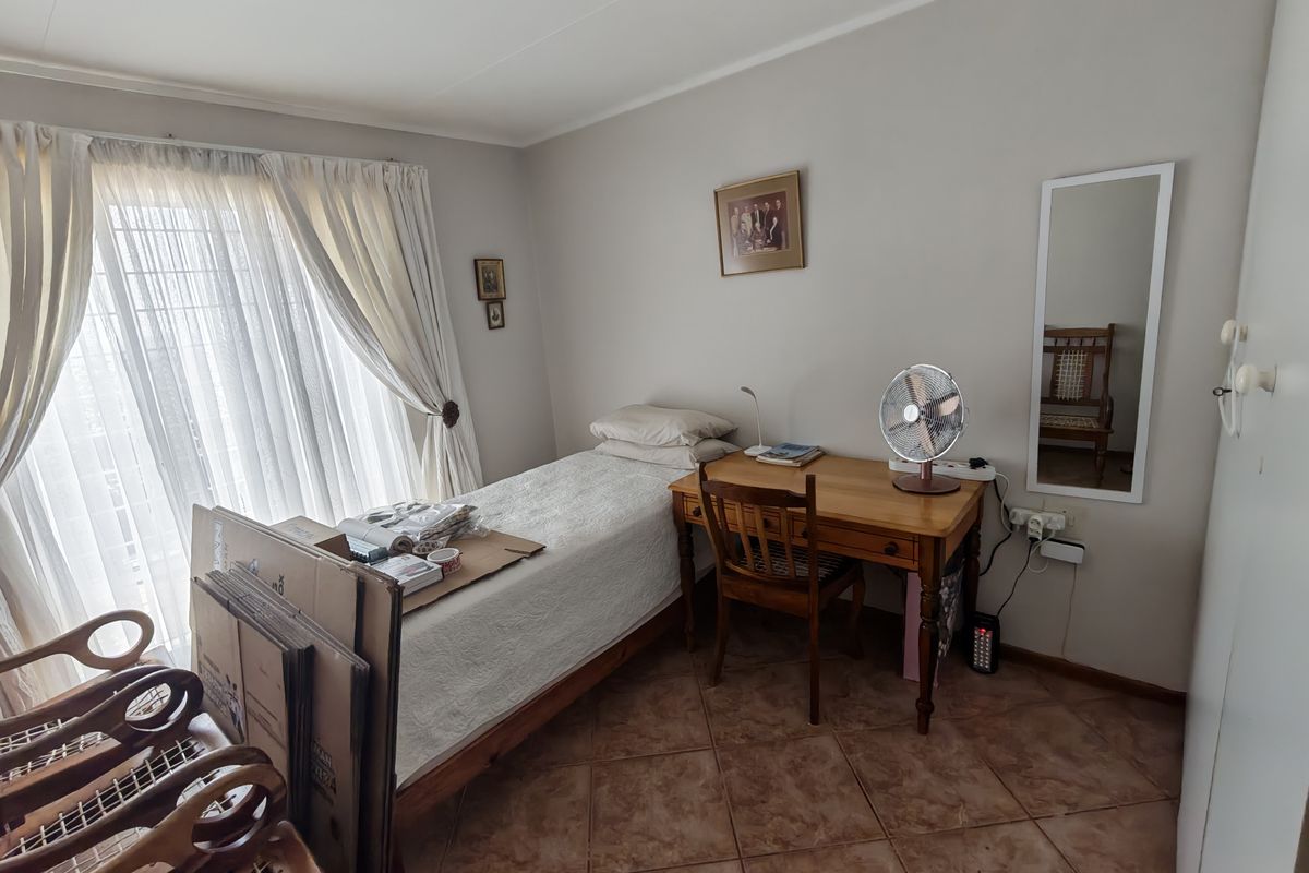 A functional bedroom featuring tiled flooring and a sliding glass door providing natural light, suitable for a comfortable retirement living space.