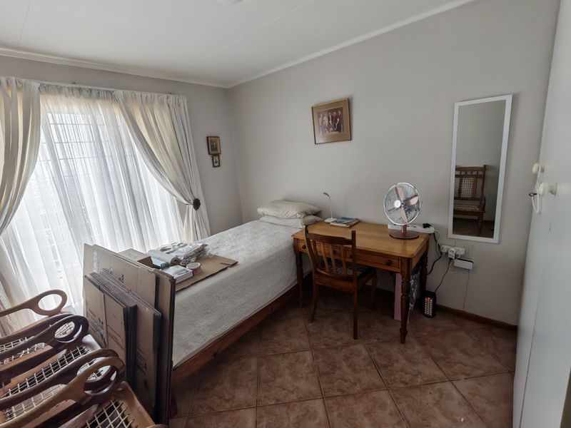 A functional bedroom featuring tiled flooring and a sliding glass door providing natural light, suitable for a comfortable retirement living space.