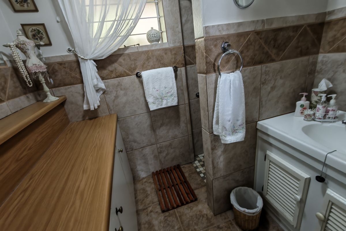 A functional bathroom featuring tiled walls and flooring, a vanity cabinet with a basin, and a dedicated shower enclosure.