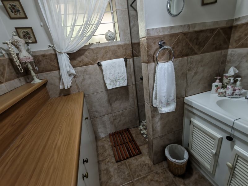 A functional bathroom featuring tiled walls and flooring, a vanity cabinet with a basin, and a dedicated shower enclosure.