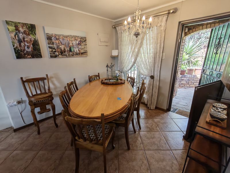 A dining room featuring ceramic tile flooring, a decorative crystal chandelier, and direct access to an outdoor patio area through a sliding glass door.