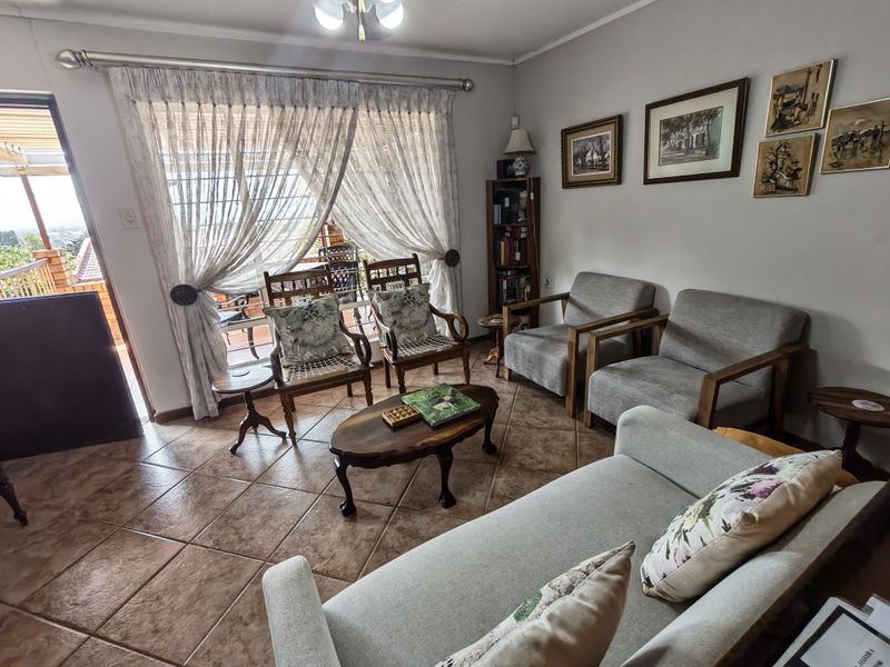A comfortable living room featuring tiled flooring and a large sliding glass door that provides access to an outdoor patio area.