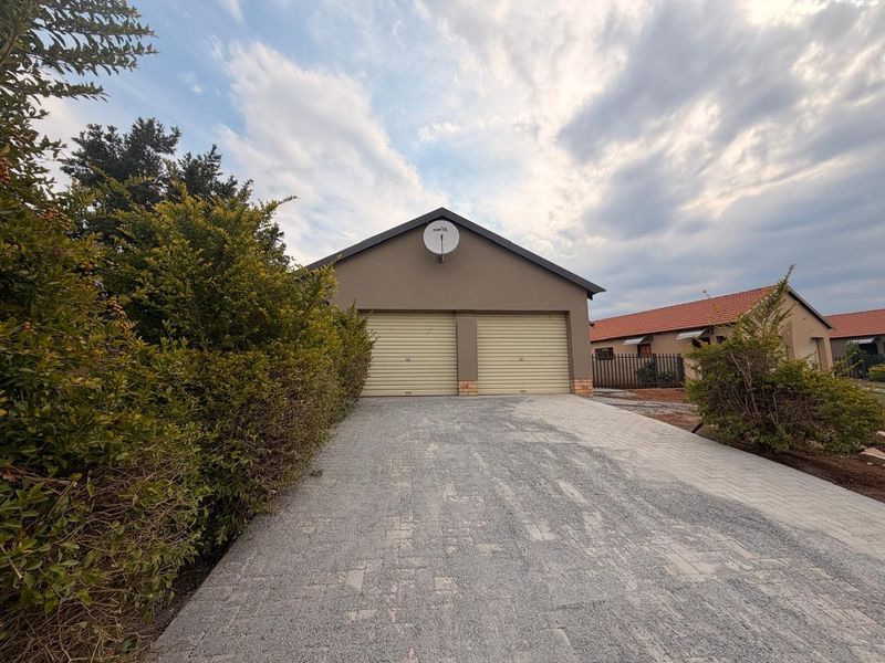A detached double garage with roller doors and a paved driveway, set within a residential property.