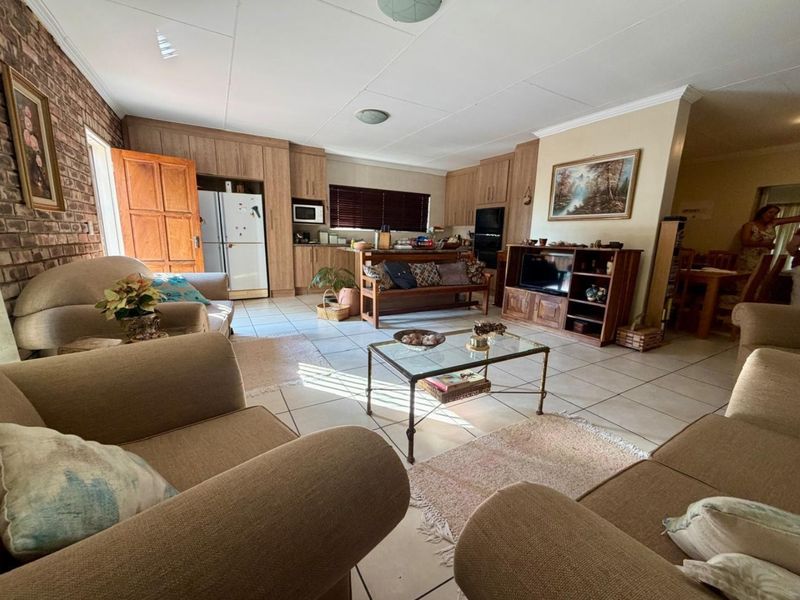 Spacious open-plan living area featuring tiled floors, an exposed brick feature wall, and an integrated kitchen with built-in cabinetry and appliances.