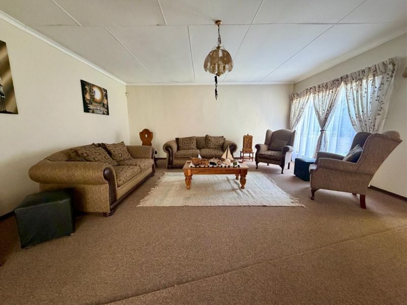 Spacious living room featuring carpet flooring, ceiling tiles, and large sliding glass doors providing natural light.