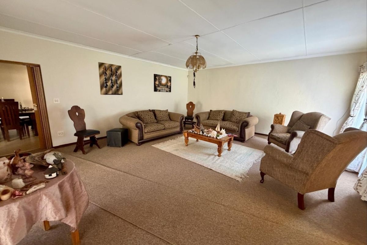 Spacious living room featuring carpeted flooring and a traditional pendant light fixture, offering a blank canvas for modern updates and interior design improvements.