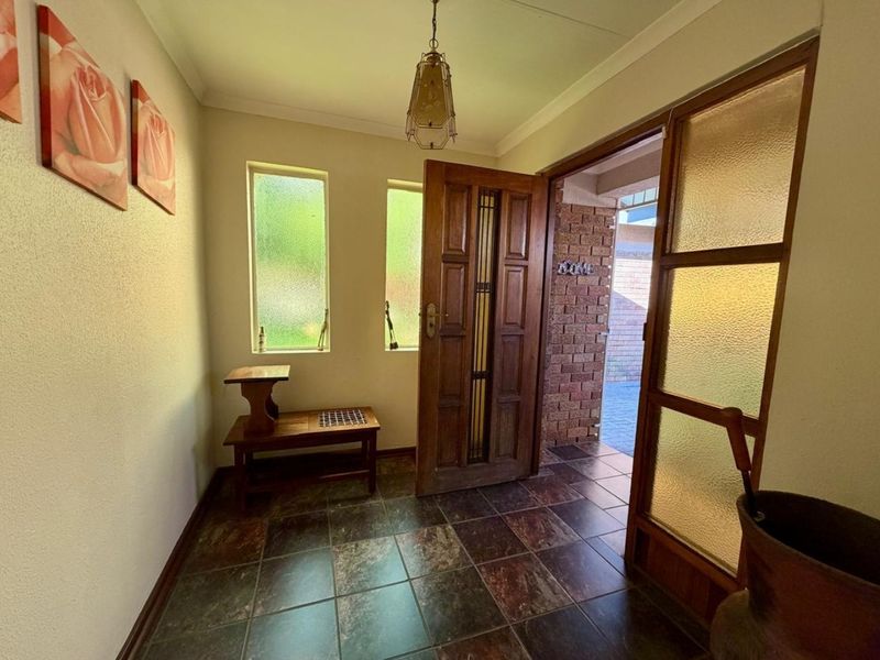 A welcoming entrance hall featuring tiled flooring, a solid timber front door, and natural light through frosted glass windows.