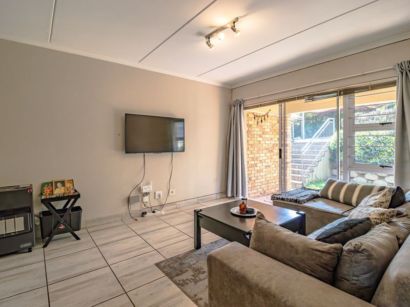 A living room featuring tiled flooring and a sliding glass door providing access to an outdoor patio area.