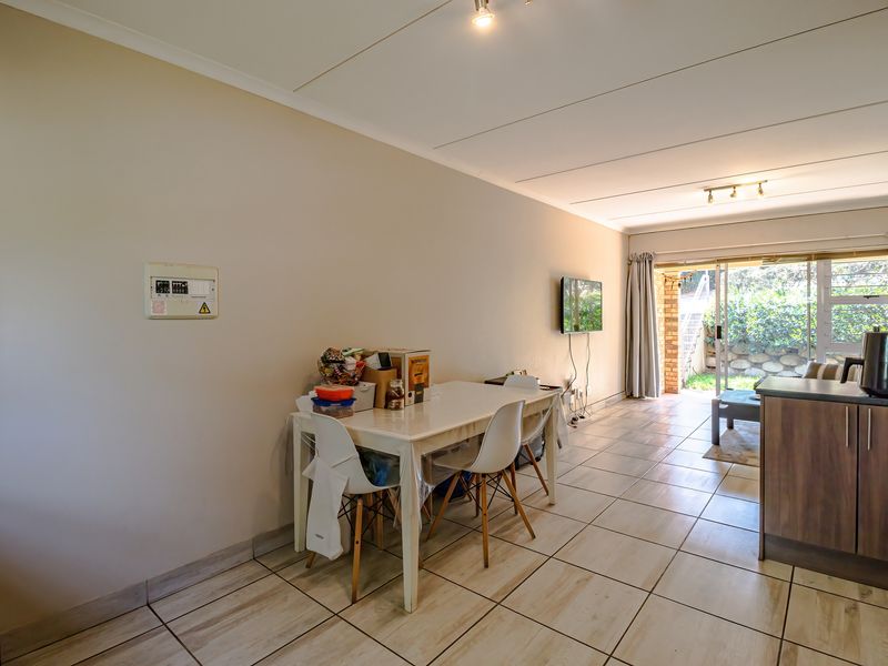 Open-plan living and dining area featuring tiled flooring, neutral walls, and a sliding glass door providing access to the outdoor space.