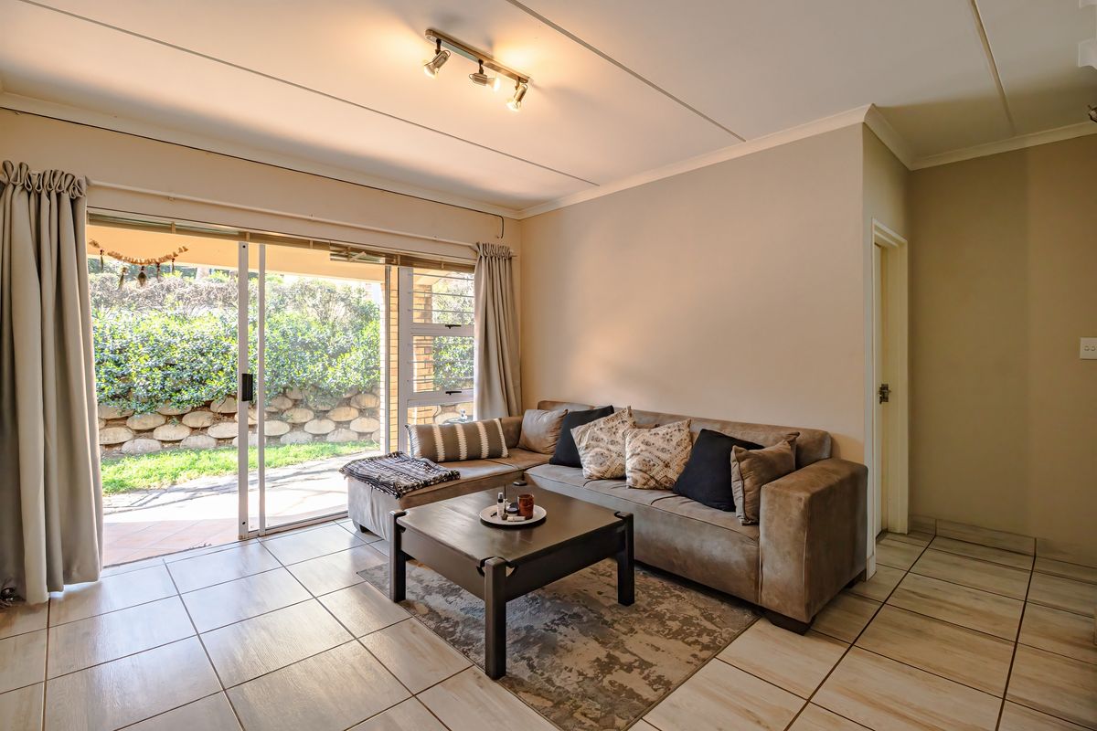 A bright living room featuring tiled flooring and a large sliding glass door providing direct access to the outdoor patio area.