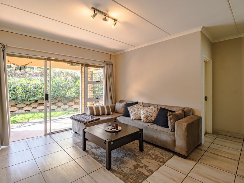 A bright living room featuring tiled flooring and a large sliding glass door providing direct access to the outdoor patio area.