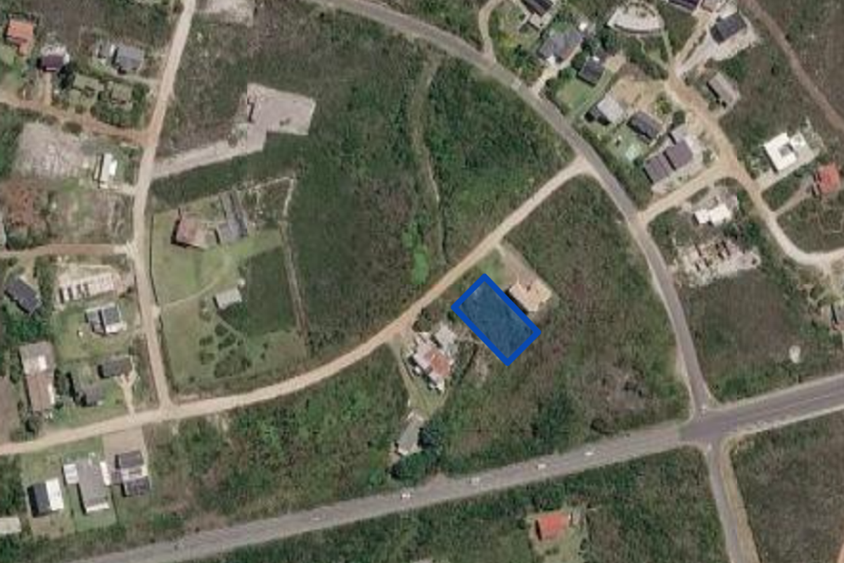 Aerial view of a vacant residential land plot highlighted in blue, situated within a developing suburban neighborhood.