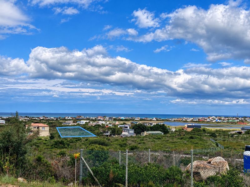 An elevated view overlooking a coastal landscape with a highlighted plot of land and distant ocean horizon.