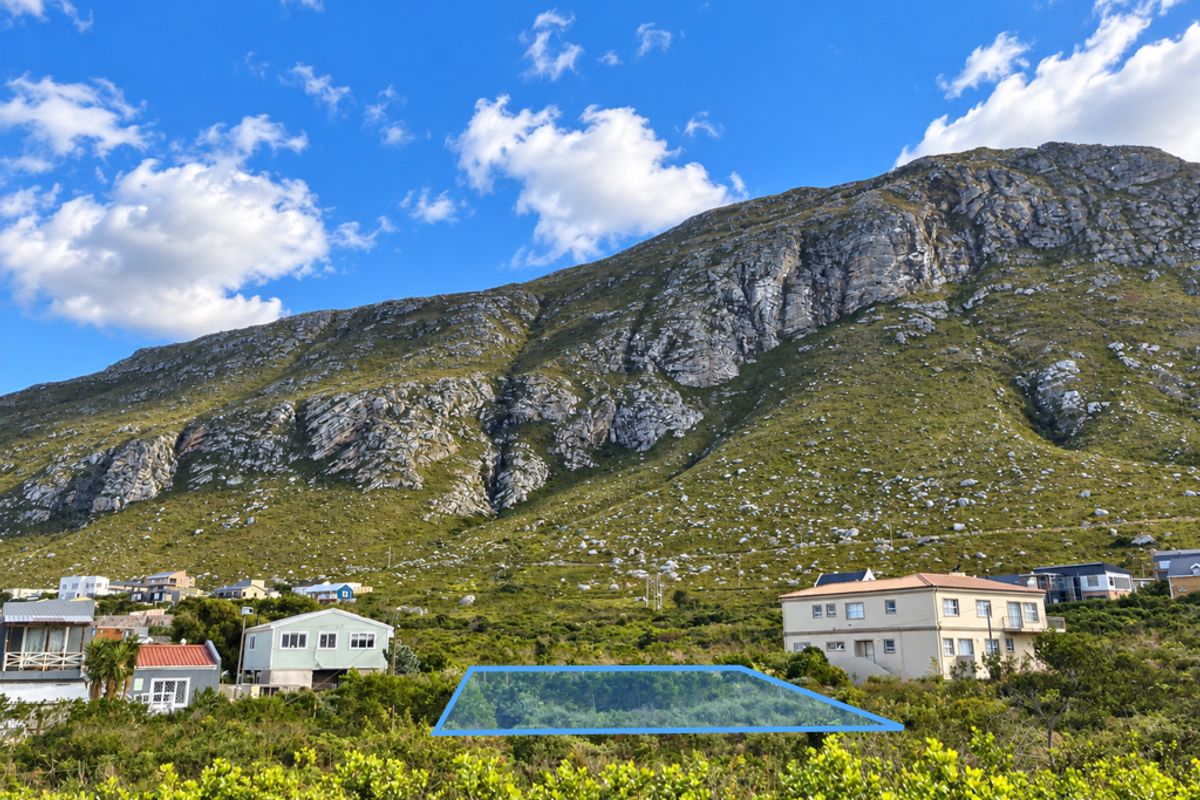 A vacant plot of land situated in a residential area with a prominent mountain backdrop.