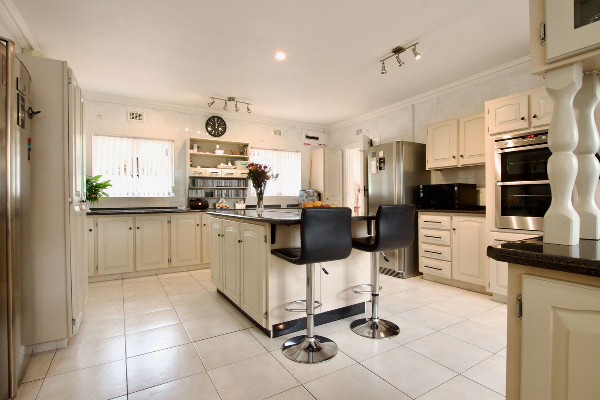 Spacious kitchen featuring a central island, built-in oven, ample cabinetry, and tiled flooring, offering a functional layout for cooking and casual dining.