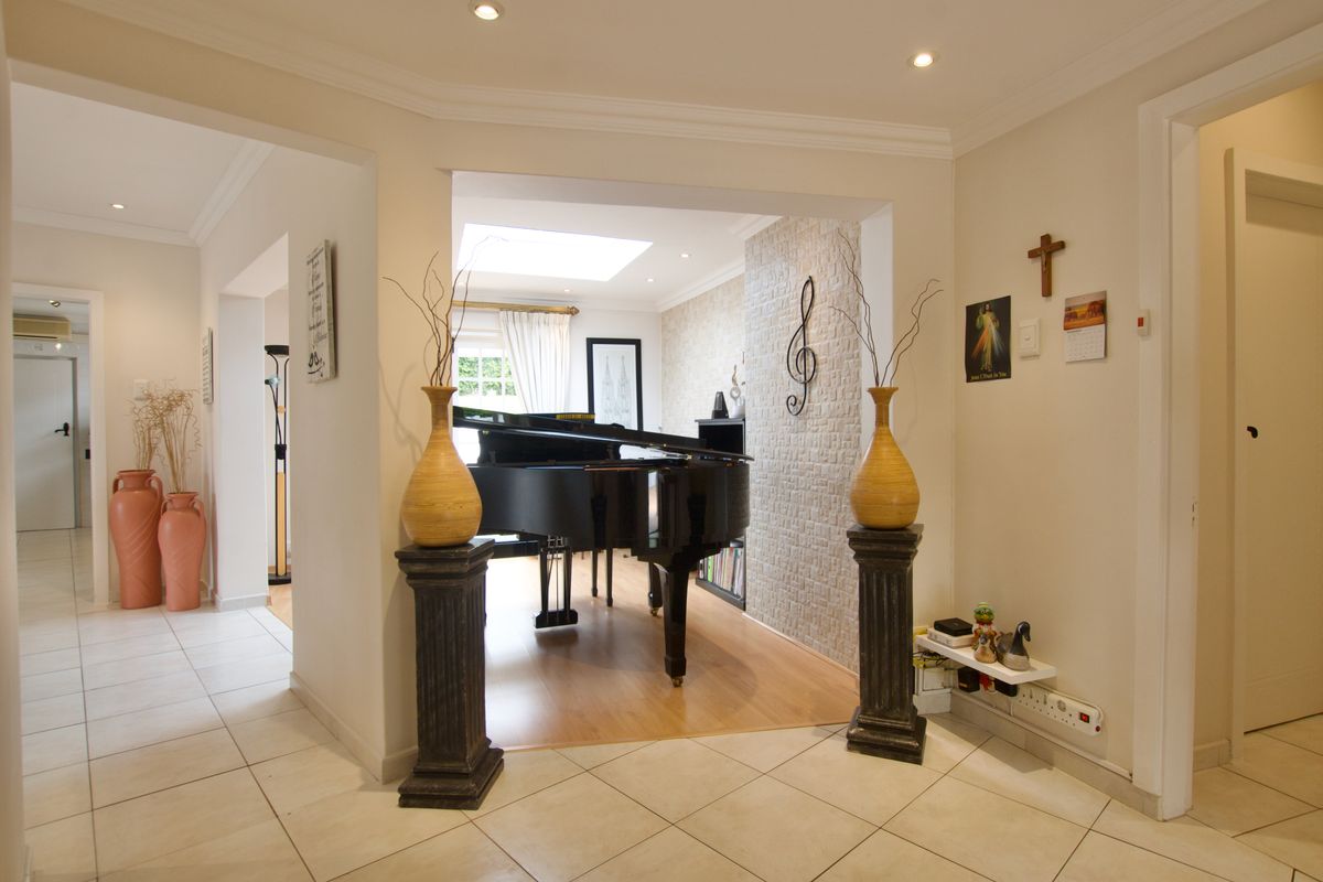 A bright living area featuring a skylight, textured stone accent wall, and a combination of tiled and laminate flooring with recessed ceiling lighting.