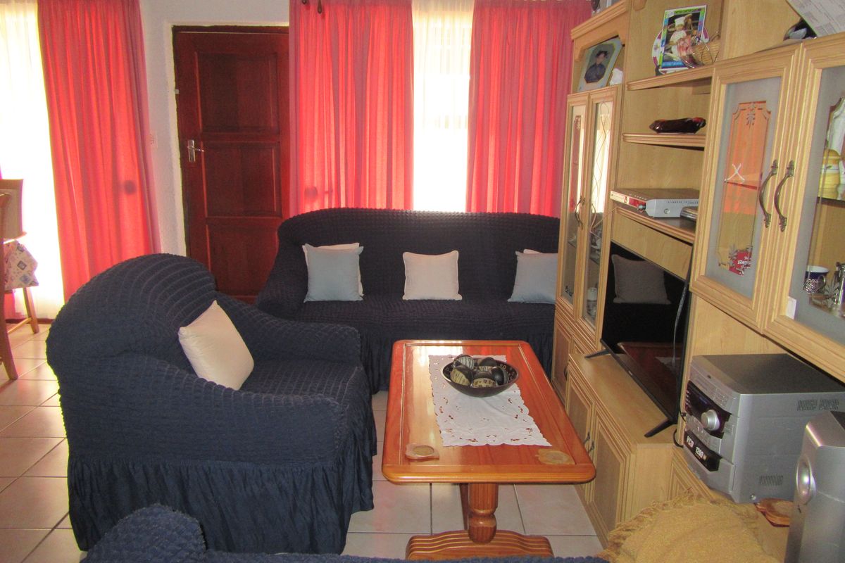 A living room featuring tiled flooring and a timber entrance door, providing a functional and traditional living space.