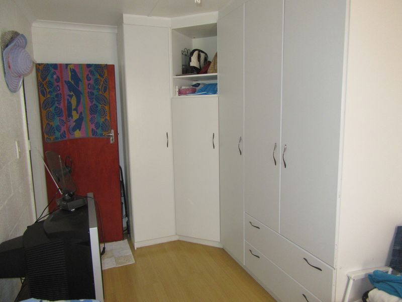 Bedroom featuring extensive white built-in cabinetry with integrated drawers and laminate flooring.