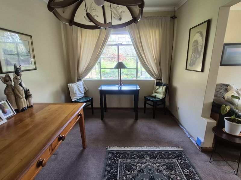 A cozy living area featuring carpeted flooring, decorative coving, and a classic leaded glass window overlooking the garden.