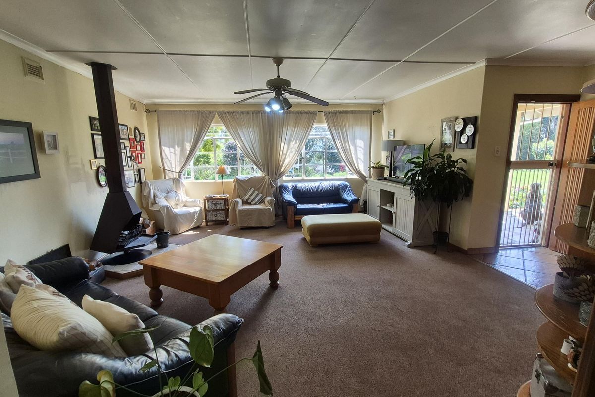 Spacious living room featuring a freestanding fireplace, ceiling fan, and direct access to the exterior through a security gate.