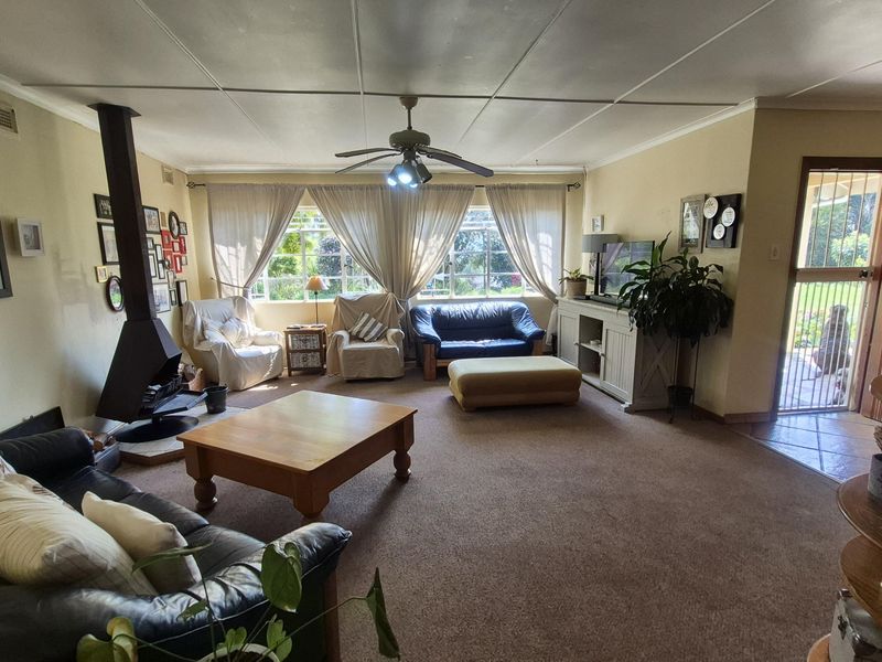 Spacious living room featuring a freestanding fireplace, ceiling fan, and direct access to the exterior through a security gate.