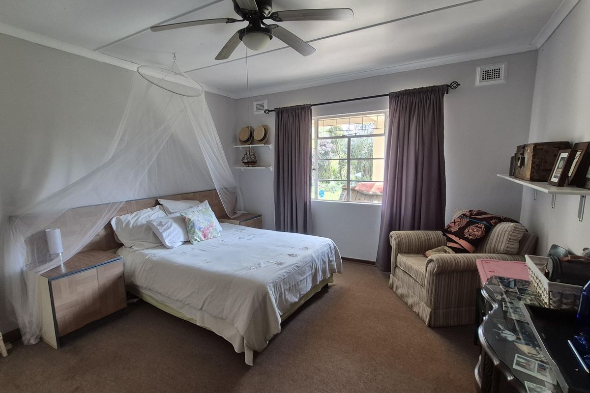 A cozy bedroom featuring a built-in headboard with integrated bedside tables, a ceiling fan, and wall-mounted shelving, offering a functional and comfortable living space.