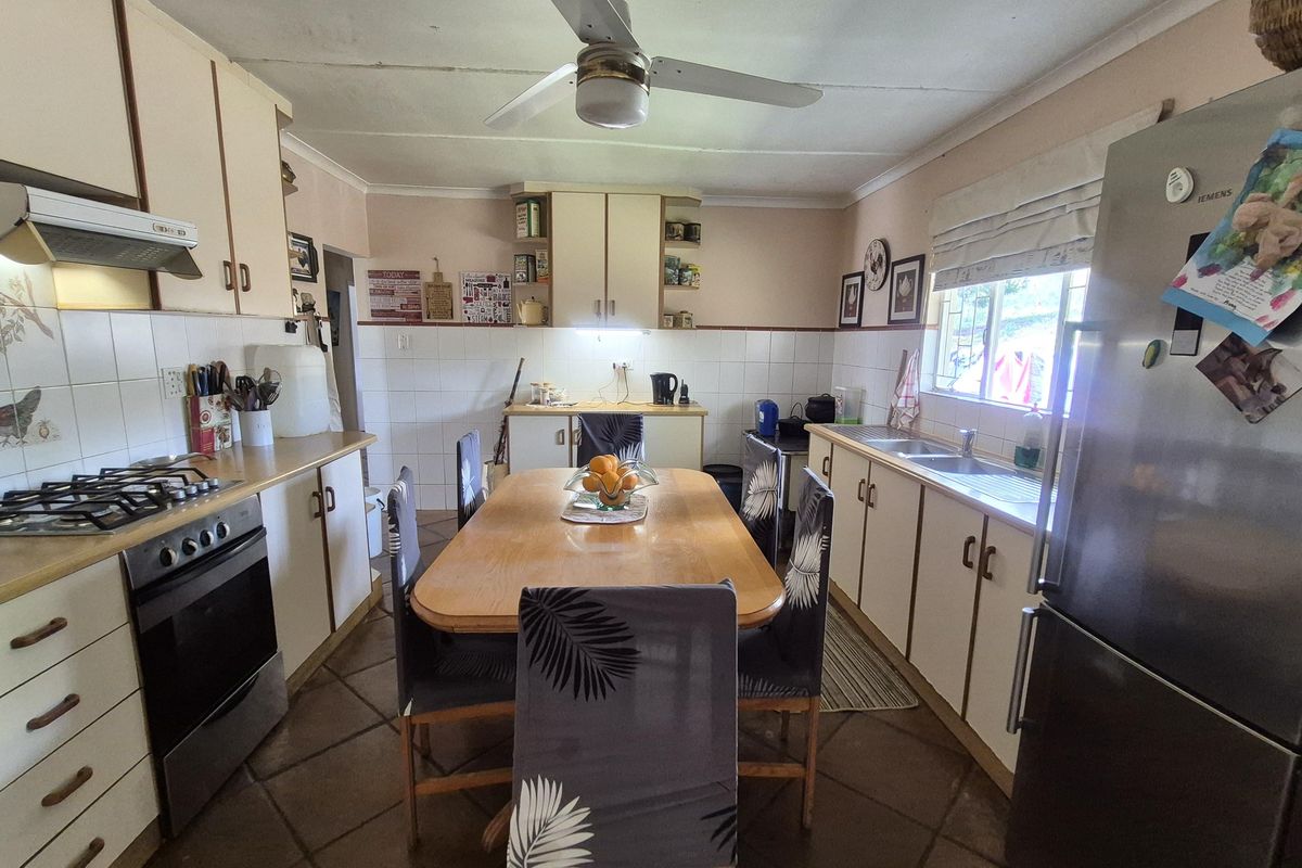 A functional kitchen featuring built-in cabinetry, a gas hob with extractor, double sink, and tiled flooring, offering a practical layout for daily meal preparation.